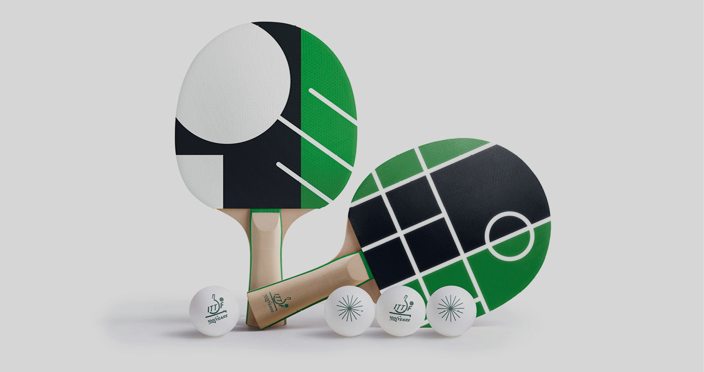 ITTF Centenary bat set with two geometric design ping pong bats in green, black and white, displayed with four branded table tennis balls.