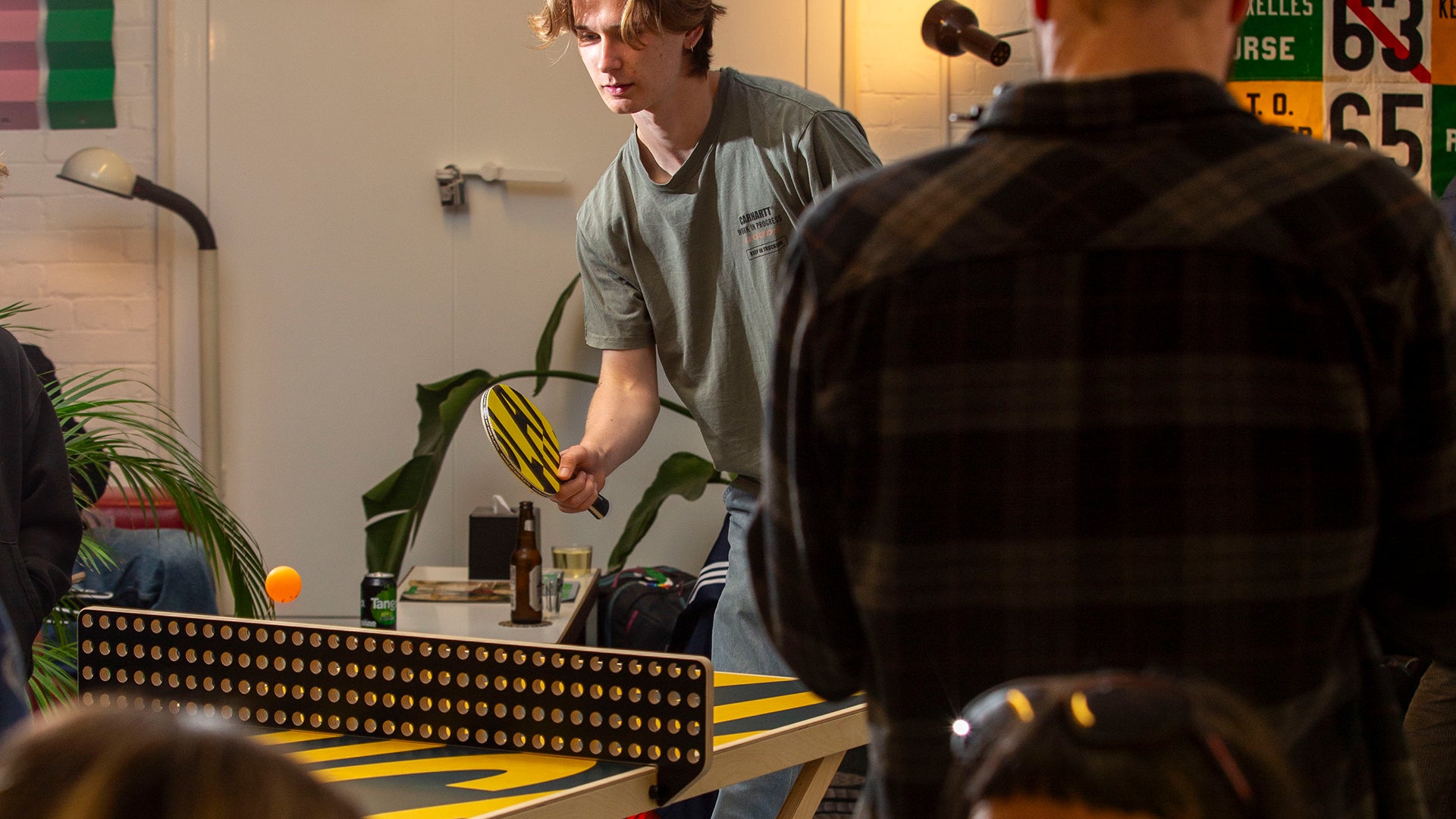 Two people playing table tennis in a casual indoor setting